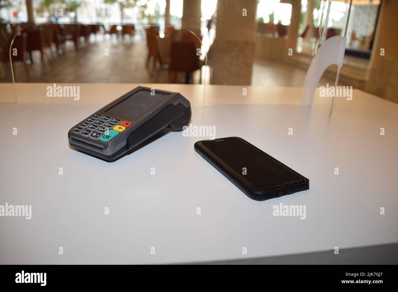 Ein Zahlungsterminal in der Nähe eines Smartphones, elektronisches Zahlungskonzept Stockfoto