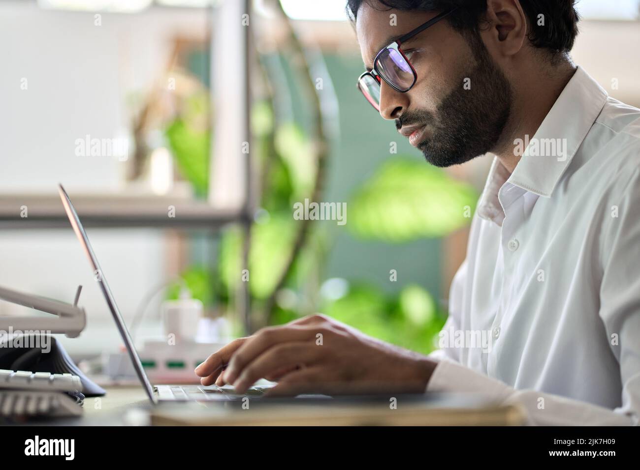 Beschäftigter indischer Geschäftsmann Programmierer, der am Schreibtisch sitzt und am Laptop schreibt. Stockfoto