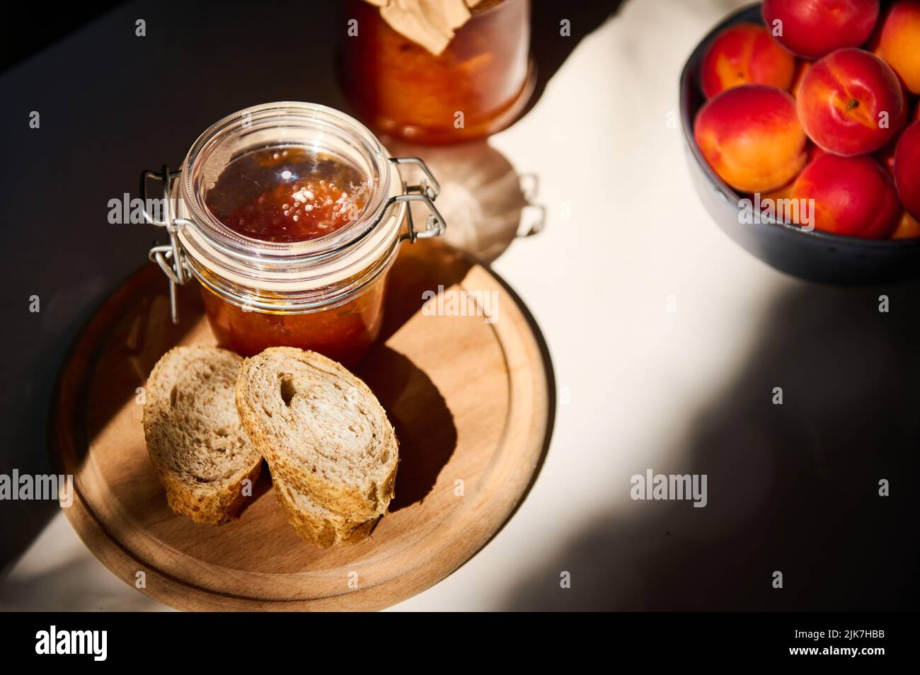 Draufsicht. Scheiben Vollkornbrot auf einem Holzbrett, ein Glas mit hausgemachter Marmelade. Stillleben durch ein Tageslicht erleuchtet Stockfoto Draufsicht. Scheiben Vollkornbrot auf einem Holzbrett, ein Glas mit hausgemachter Marmelade. Stillleben durch ein Tageslicht erleuchtet Stockfoto
