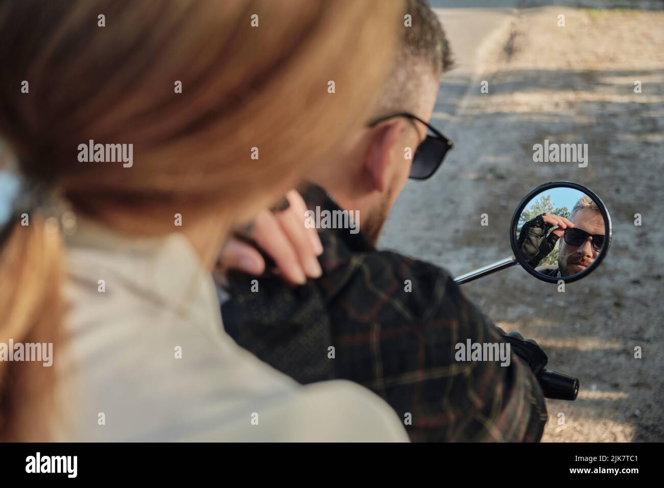 Ein Paar schaut in den Spiegel eines Motorrads, ein Paar mittleren Alters reist zusammen Stockfoto