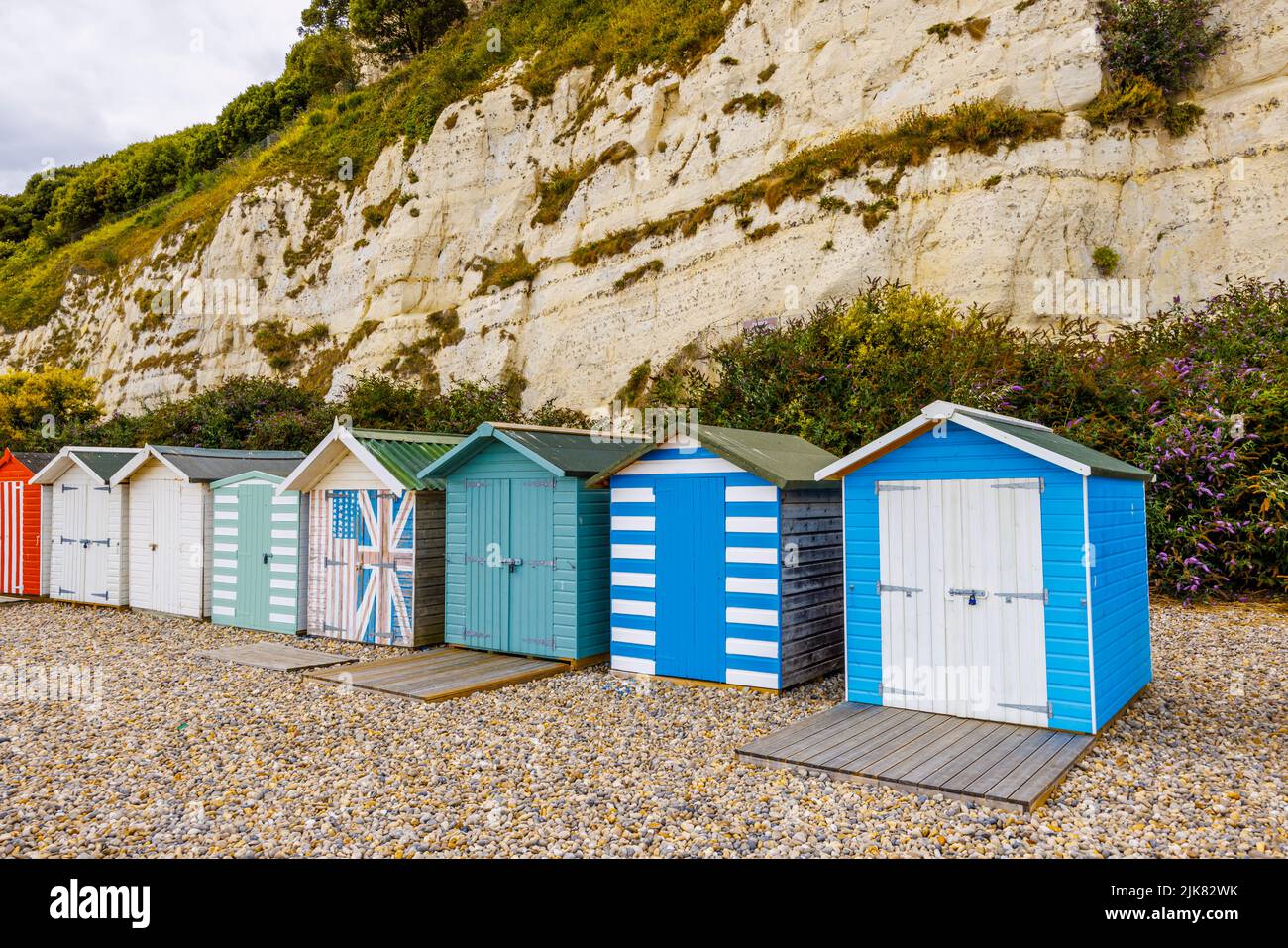 Eine Reihe von Strandhütten am Fuße der Kreidefelsen bei Beer, einem kleinen Küstendorf an der Lyme Bay an der Jurassic Coast of East Dorset, Südwestengland Stockfoto