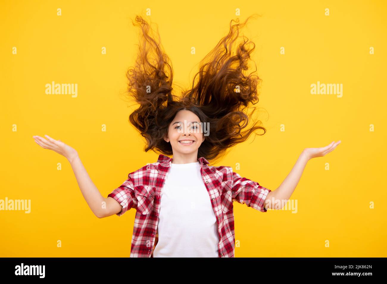 Teenager-Porträt mit verrückten Bewegung Haare. Junge Teenager-Kind mit fließenden Haaren. Brünette teen Mädchen flatternde Haare in Bewegung, isoliert auf gelb Stockfoto
