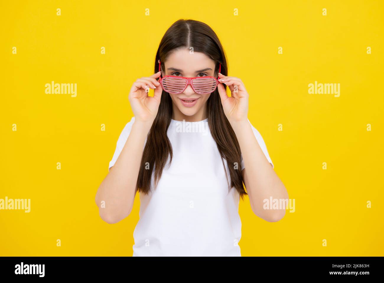 Frau fühlt sich cool und genial. Aufgeregt glücklich lustige junge Frau in Party-Brille auf einem gelben hellen Hintergrund. Stockfoto