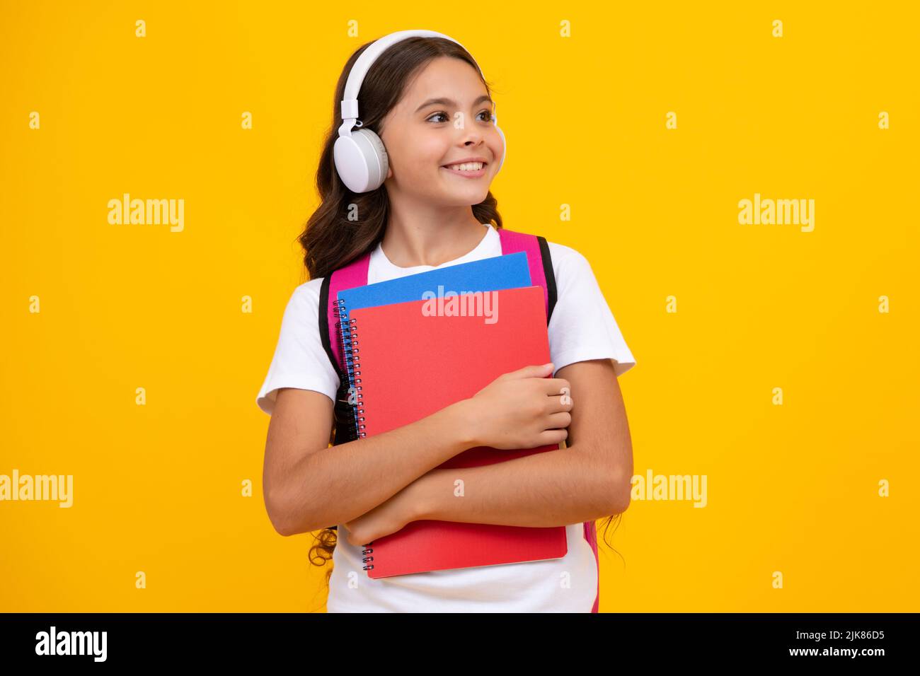 Schulmädchen, Teenager 12, 13, 14 Jahre alt, in Kopfhörern und Büchern auf isoliertem Studiohintergrund. Schulkinder mit Rucksack. Stockfoto