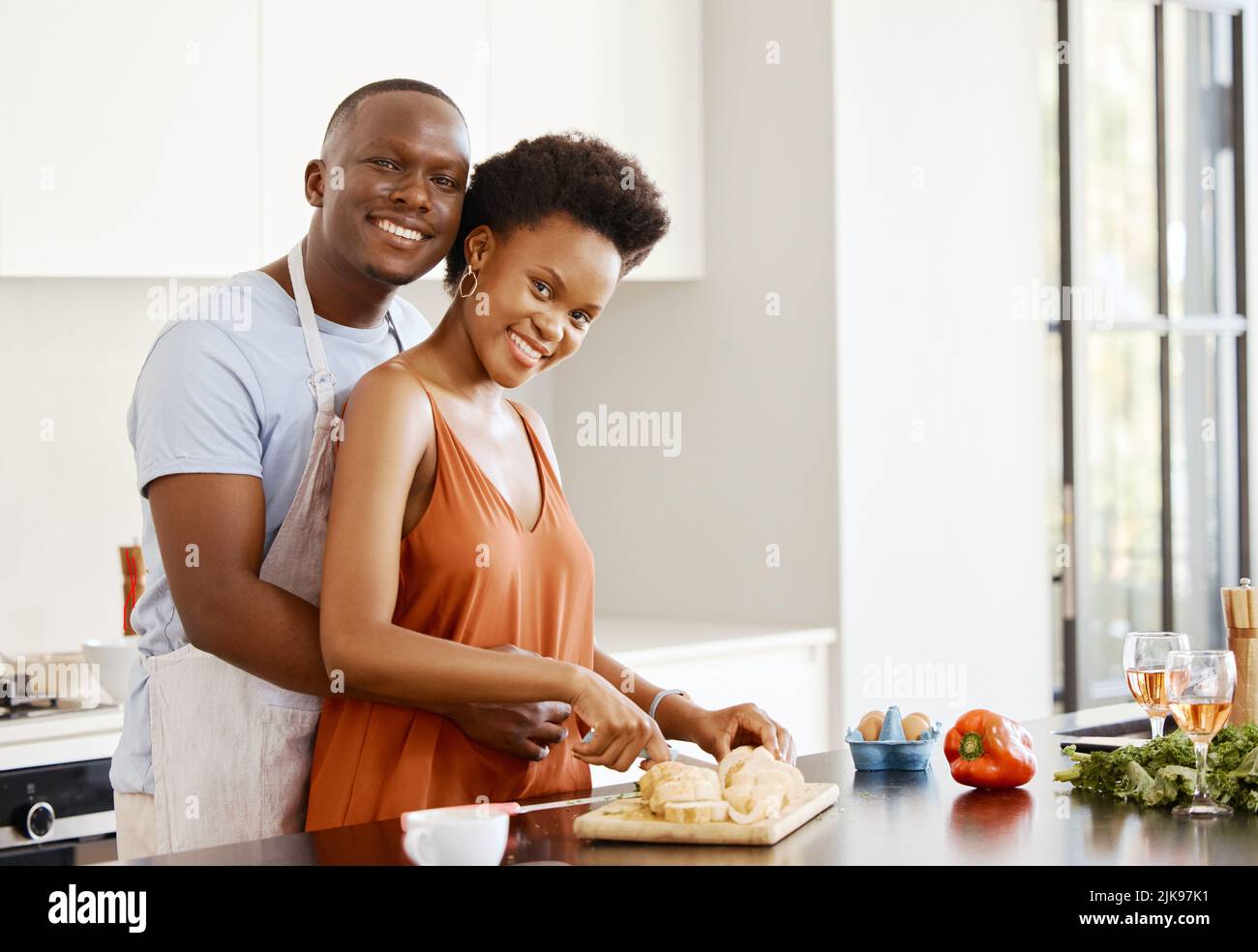 Sie passt mir wie ein Handschuh. Ein junges Paar umarmt sich in der Küche und macht zu Hause Essen. Stockfoto