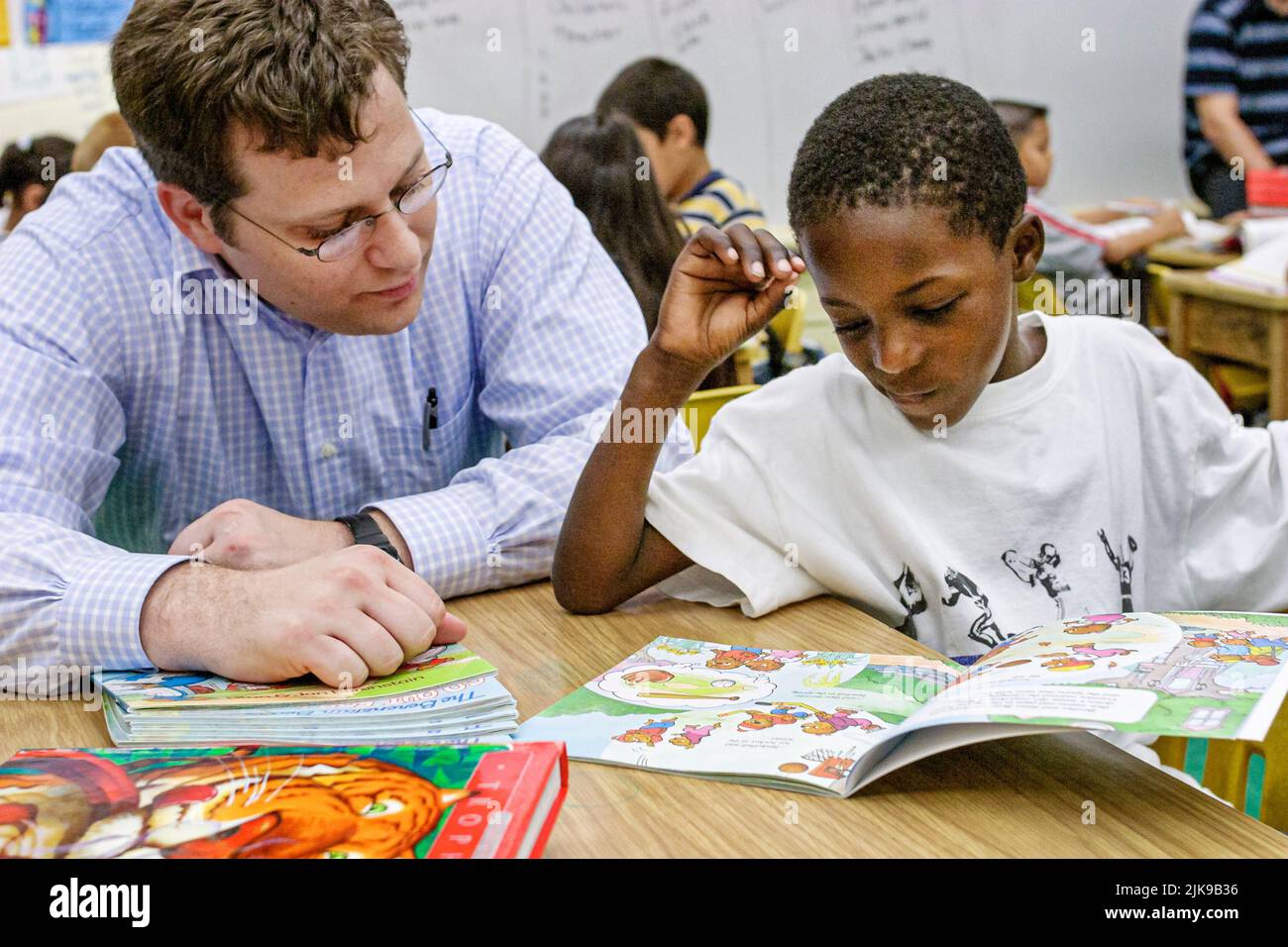 Miami Florida, Frederick Douglass Elementary School, Gemeinschaft mit niedrigem Einkommen, Schwarzer Student Boy beim Lesen von Klassenzimmern, Mann von der Anwaltskanzlei, der Bücher spendete Stockfoto