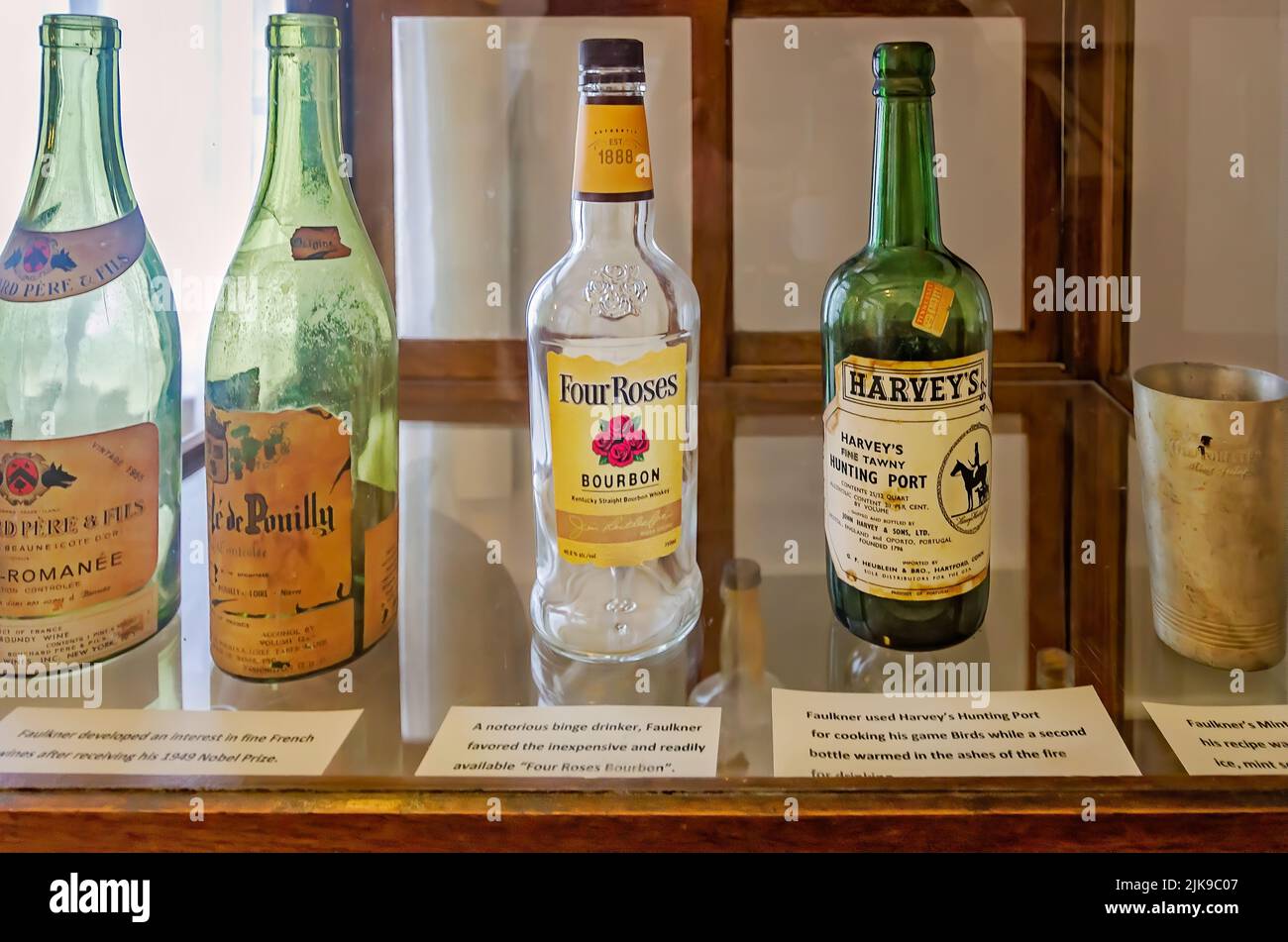 Alkoholflaschen und eine Minze-Julep-Tasse werden in einem Glasgehäuse in Rowan Oak, der Heimat des Schriftstellers William Faulkner in Oxford, Mississippi, ausgestellt. Stockfoto