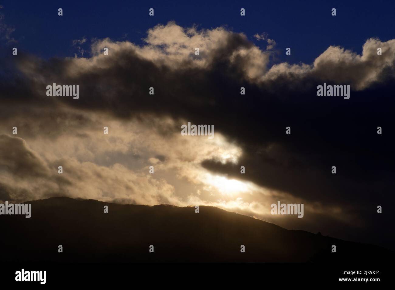 Hügel werden durch Wolken, die sich über den Himmel bewegen und die Sonne blockieren, in den Schatten gestellt. Stockfoto