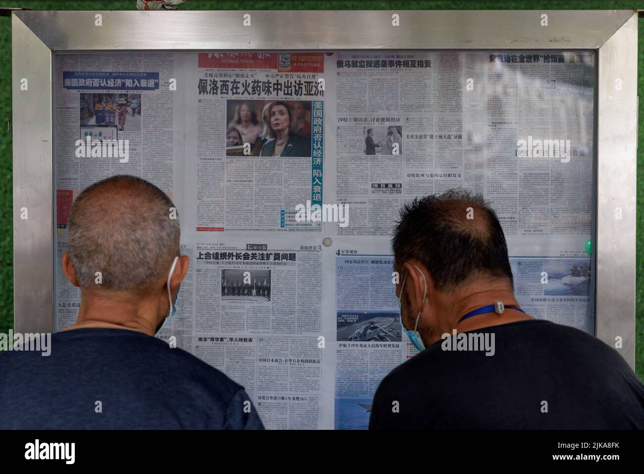 Männer lasen die Zeitung Global Times, die einen Artikel auf der Titelseite über die Asien-Tour der Sprecherin des US-Repräsentantenhauses, Nancy Pelosi, an einer Straßenwand in Peking, China, am 1. August 2022, enthält. Auf der Titelseite heißt es: 'Pelosi besucht Asien im Geruch von Schießpulver.' REUTERS/Thomas Peter TPX-BILDER DES TAGES Stockfoto