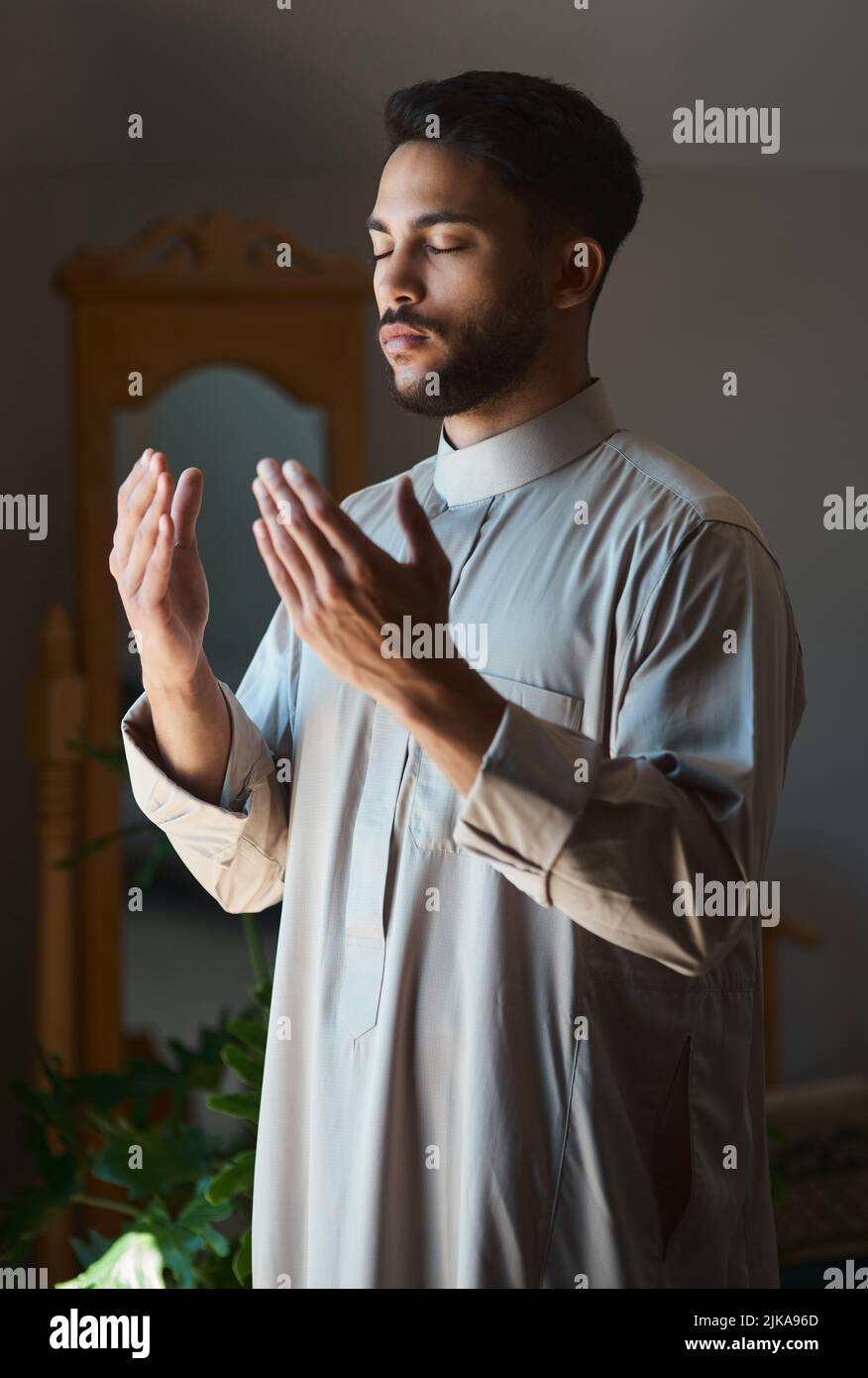 Das Gebet vergrößert das Herz. Ein junger muslim, der zu Hause im Wohnzimmer betet. Stockfoto