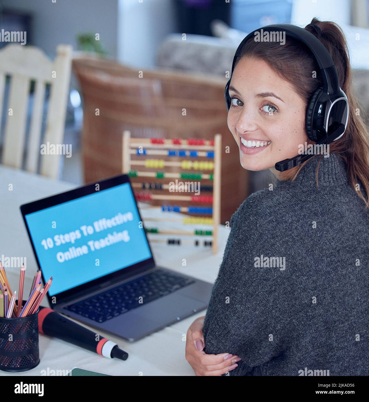 Die Lehrerin ist das Herz des Bildungssystems. Eine junge Lehrerin, die zu Hause mit ihrem Laptop einen Online-Unterricht unterrichtet. Stockfoto