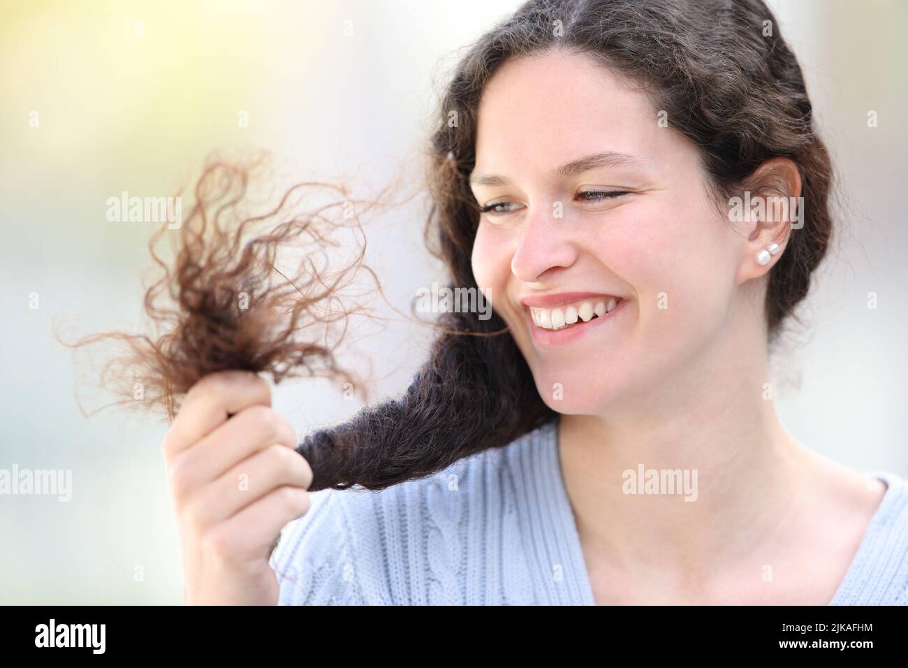 Glückliche Frau, die ihr Haar auf der Straße ansieht Stockfoto