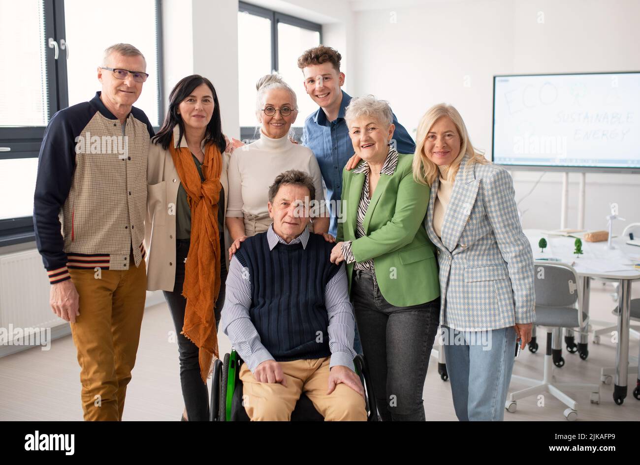 Glückliche ältere Studenten treffen sich mit ihrem Freund im Rollstuhl an der Universität. Stockfoto