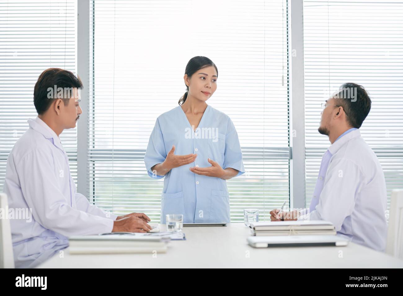 Hübsche Ärztin, die vor Kollegen spricht Stockfoto