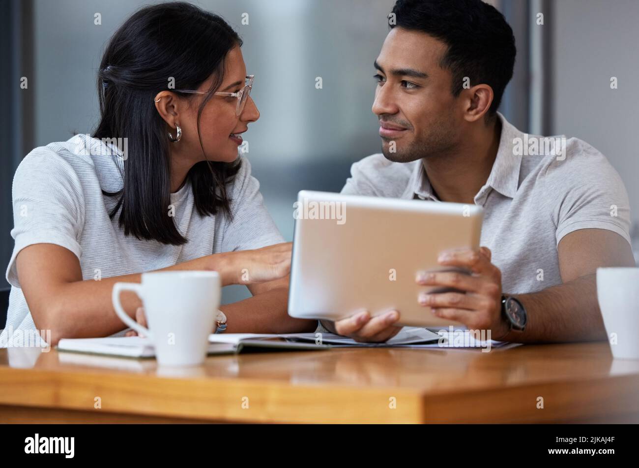 Mögen Sie meine Weisheitsworte verfolgen: Zwei Geschäftsleute, die in einem modernen Büro an einem Schreibtisch sitzen. Stockfoto