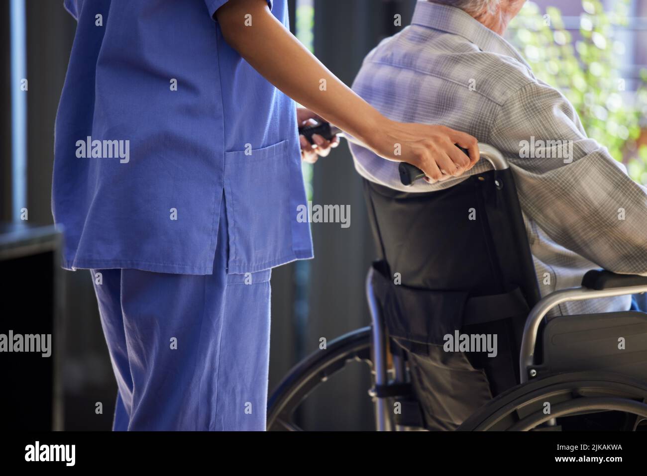 Eine Krankenschwester, die ihrer Patientin im Rollstuhl hilft. Stockfoto