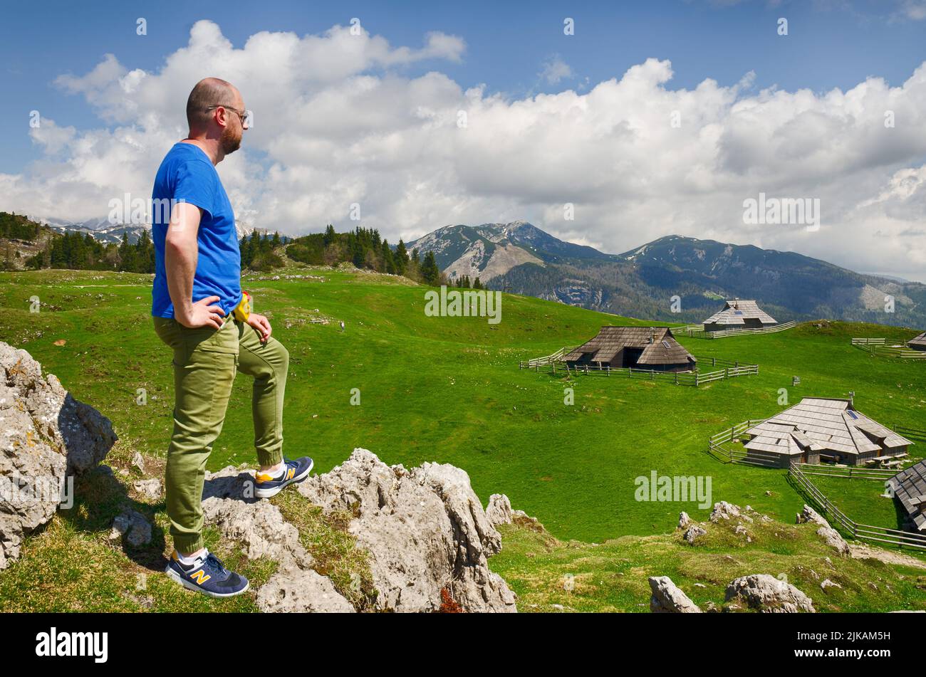 Der Mensch genießt den Blick auf das alpine Dorf in den Bergen. Velika Planina oder großes Weideplateau in den Kamnik Alpen, Slowenien. Stockfoto