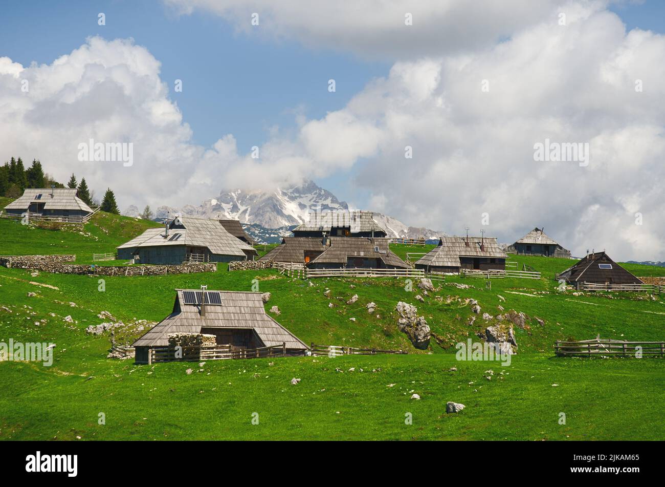Großes Weideplateau in den Kamnikalpen, Slowenien. Berghütte oder Haus auf grünem Hügel. Alpine Wiesenlandschaft. Ökologischer Landbau. Stockfoto