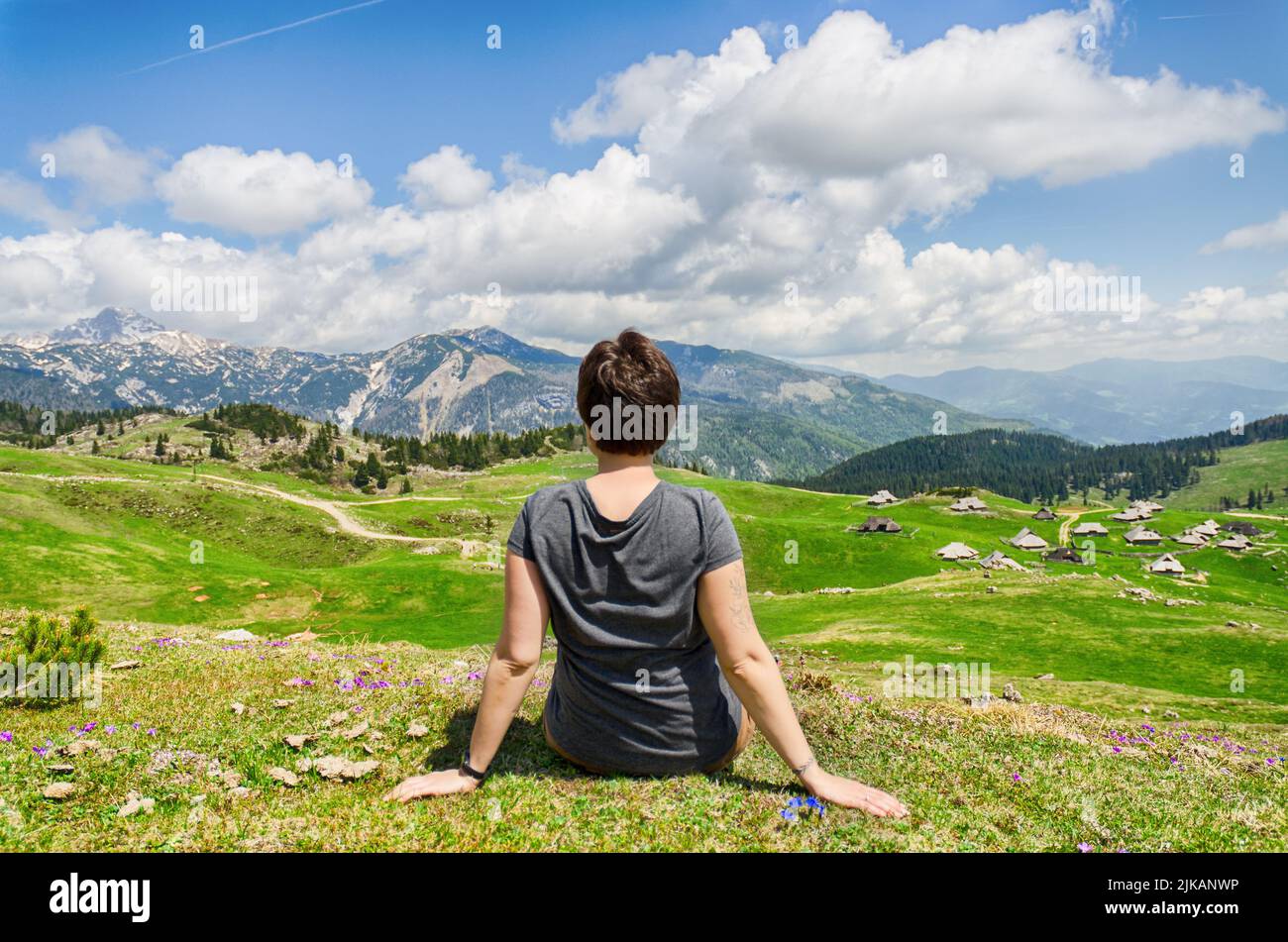 Die Frau genießt den Blick auf das Bergdorf. Velika Planina oder großes Weideplateau in den Kamnik Alpen, Slowenien. Berghütte Stockfoto