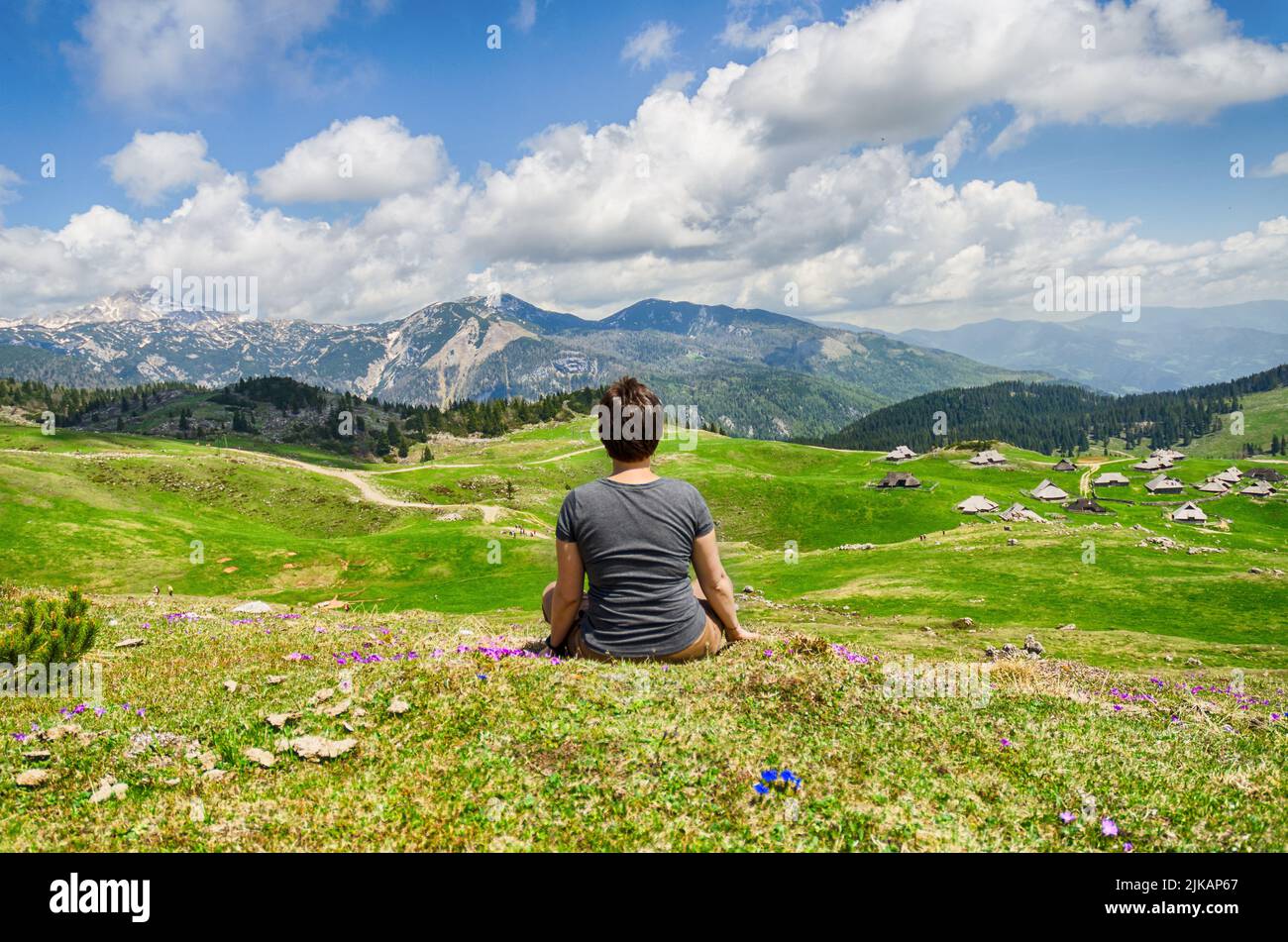 Die Frau genießt den Blick auf das Bergdorf. Velika Planina oder großes Weideplateau in den Kamnik Alpen, Slowenien. Berghütte Stockfoto