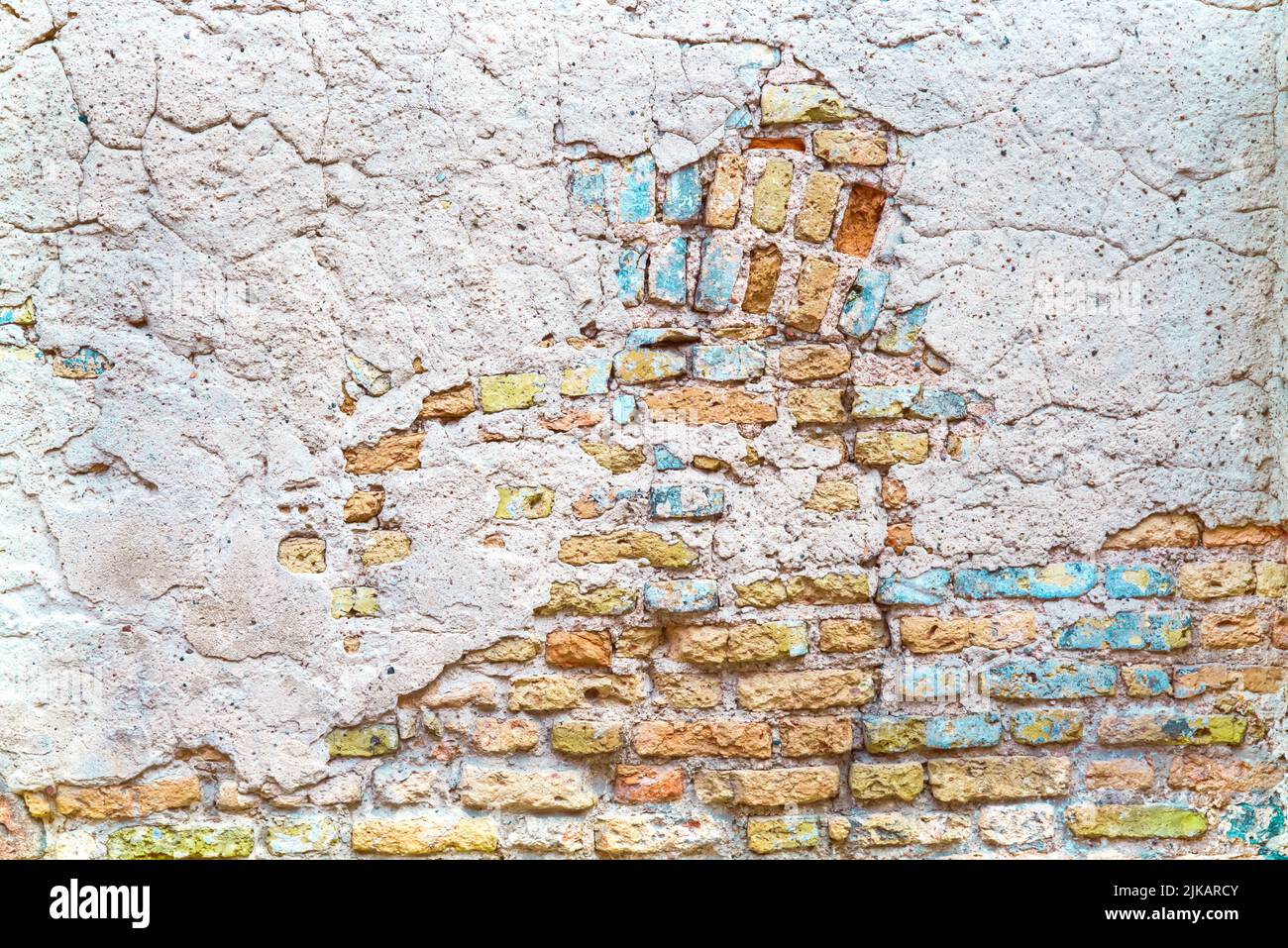 Alte Backsteinmauer mit blauen und gelben Putzlacken Stockfoto