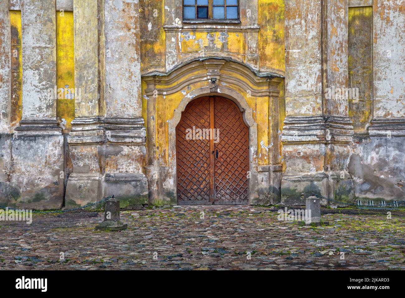 Antiker Eingang zum historischen Gebäude Altstadt von Vilnius. Schwere braune Holztür und alte raue Steinmauer Stockfoto