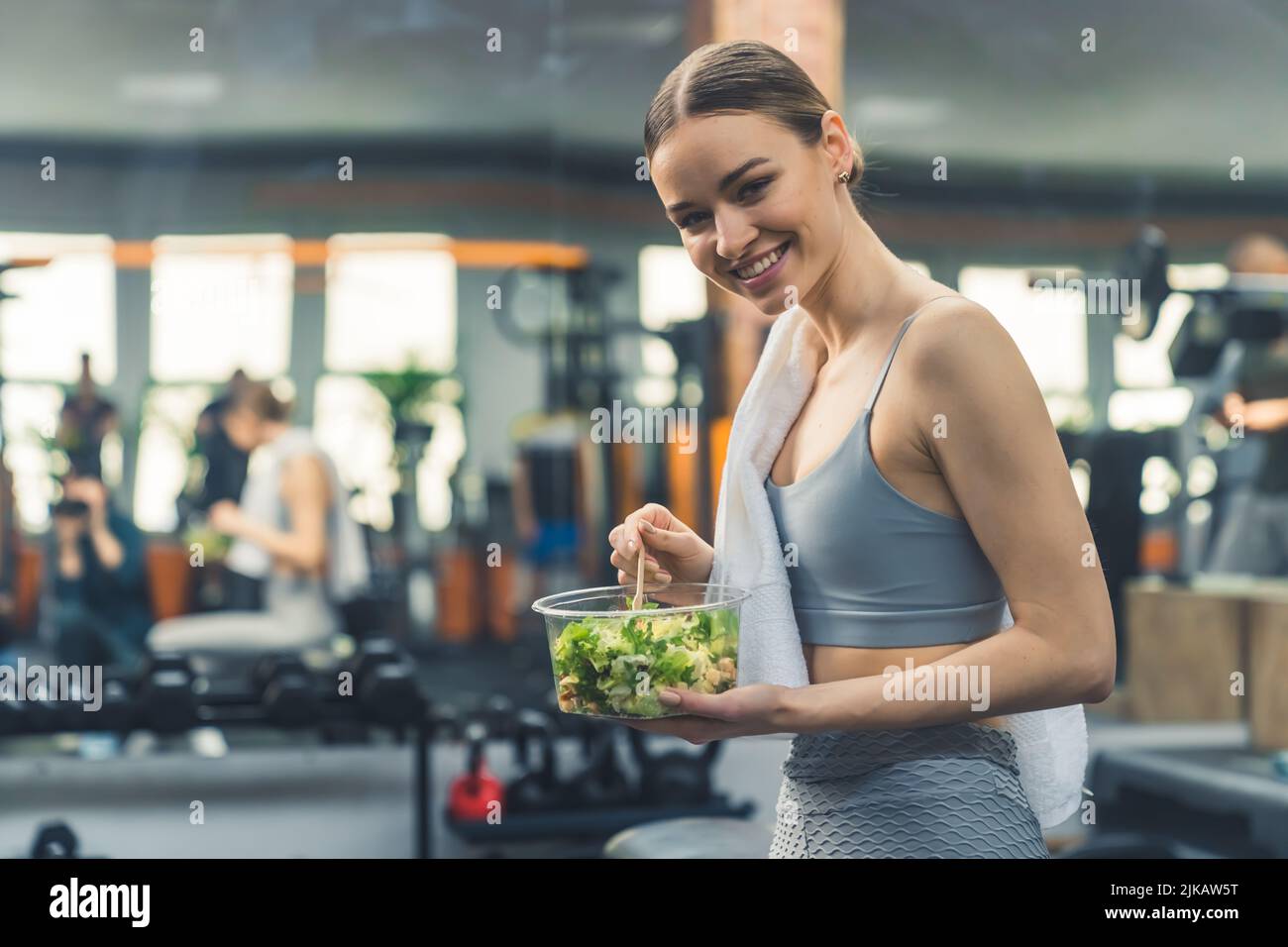 Junges glückliches Mädchen, das gesunde Nahrung isst und sich nach dem Training ausruht. Hochwertige Fotos Stockfoto