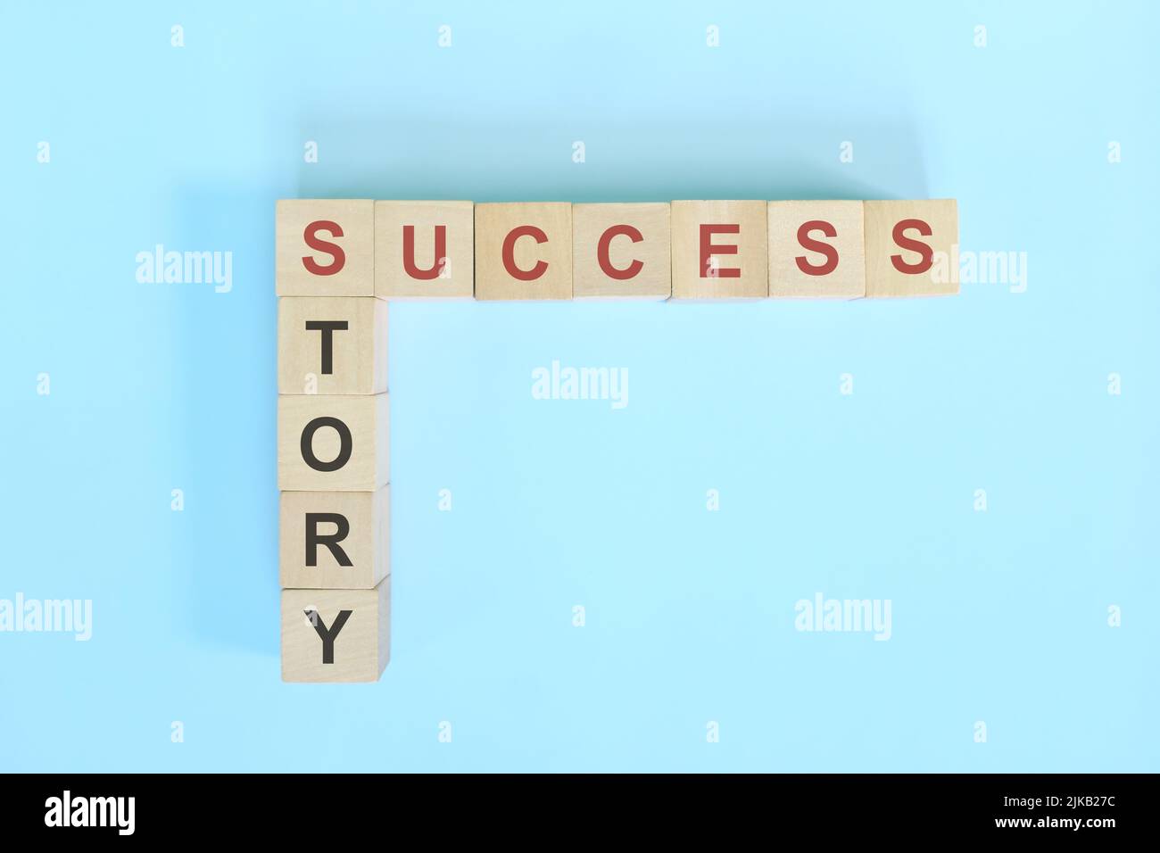 Erfolgsgeschichte im Lebens-, Geschäfts- und Karrierekonzept. Holzblock Kreuzworträtsel flach lag auf blauem Hintergrund. Stockfoto