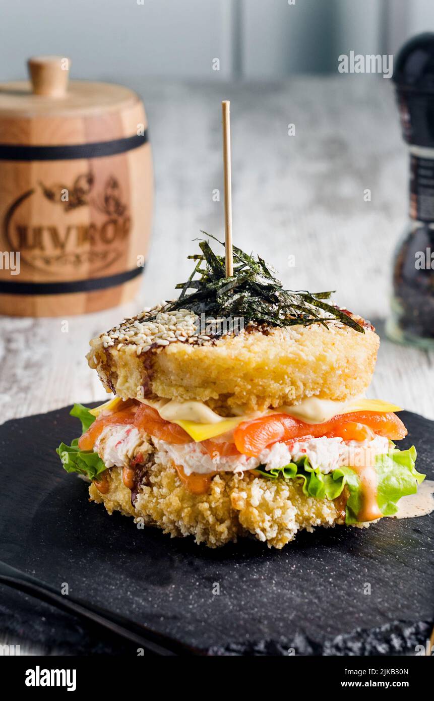 Sushi-Burger aus Reisbrot mit Lachs, Salat und Wasabi-Sauce. Sushi-Food Hybriden Trend. asiatische Stil glutenfrei. Stockfoto