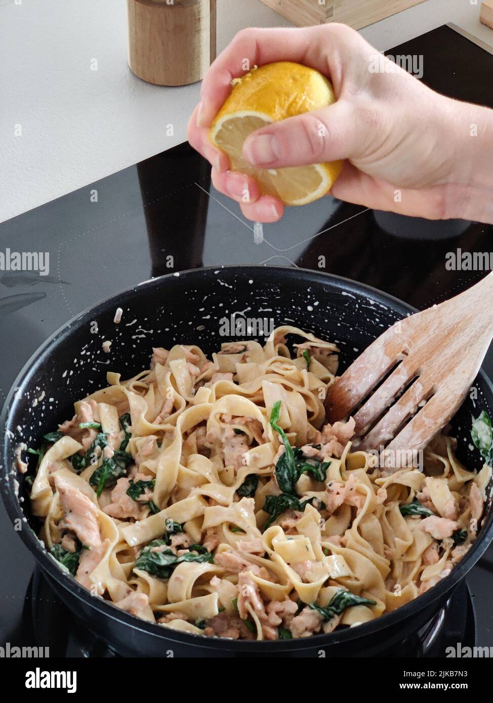 Frau drückt eine Zitrone auf leckere hausgemachte Meeresfrüchte-Pasta in der eigenen Küche, Nahaufnahme Stockfoto