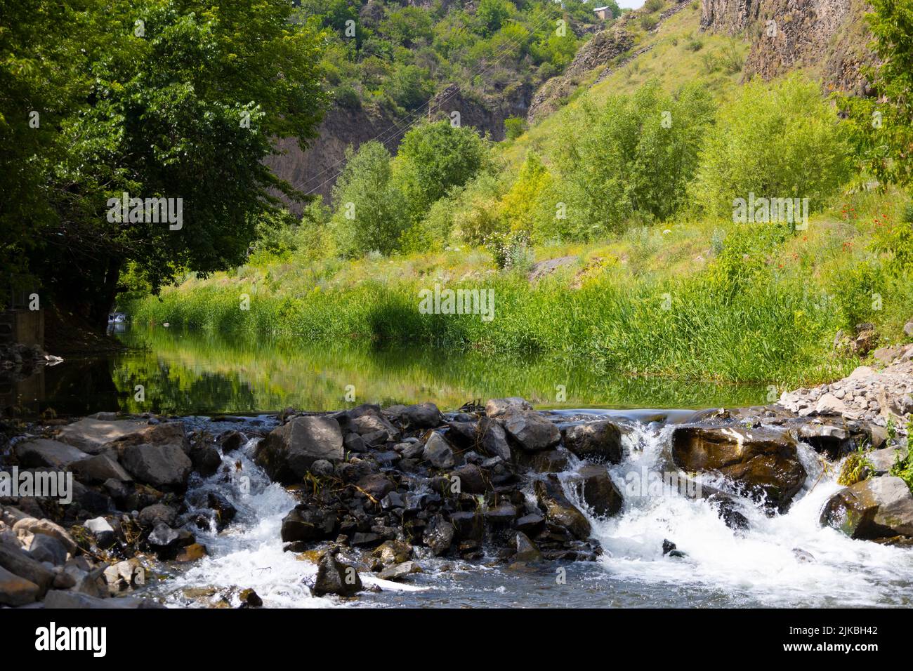 Ein kleiner Wasserfall mit hohen Felsen im Hintergrund Stockfoto