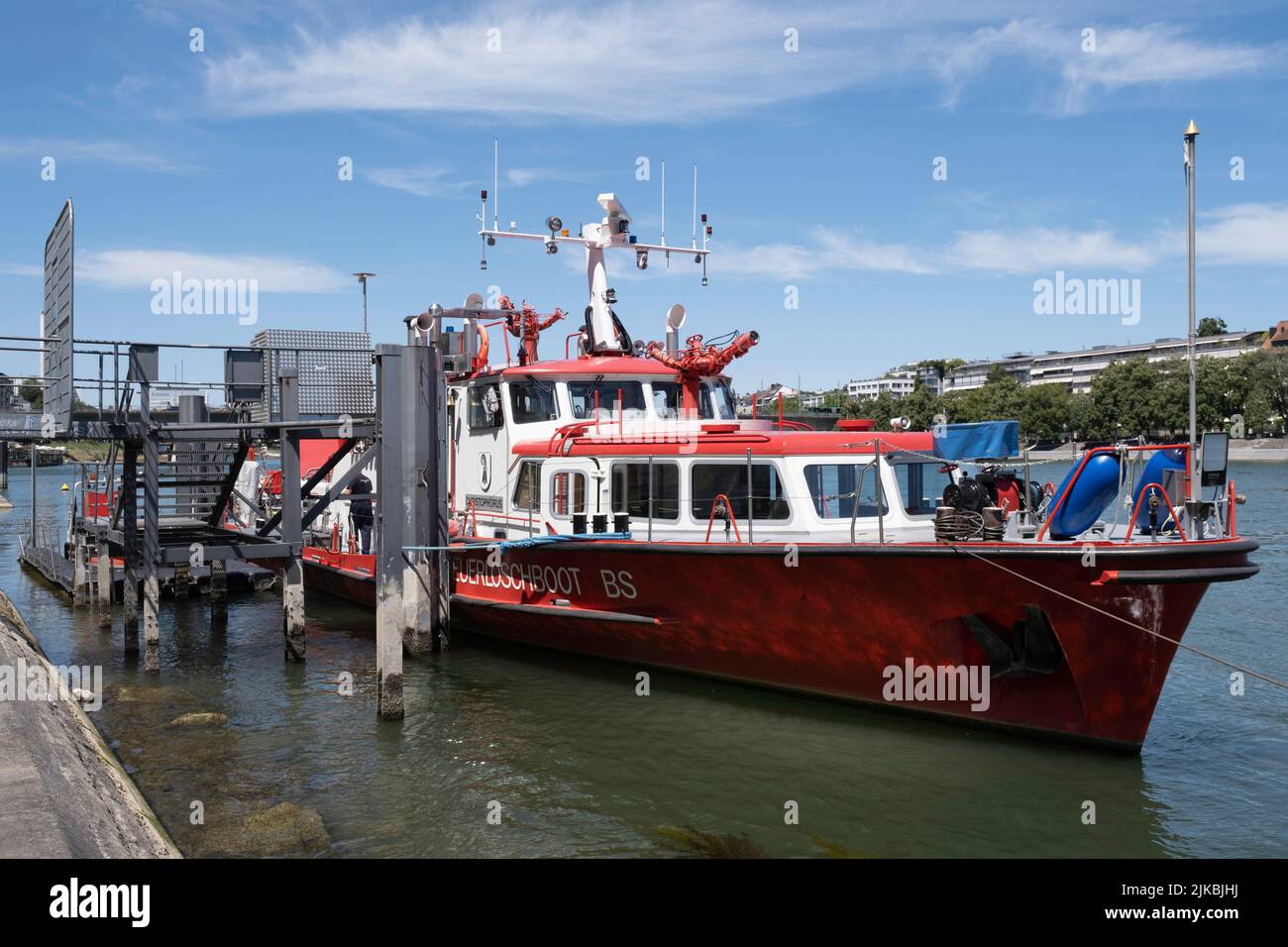 Rot-weißes Feuerlöschboot mit kleineren Gummilifebooten, die an einem sonnigen Sommertag am Rheinufer in der Stadt Basel festgemacht wurden Stockfoto