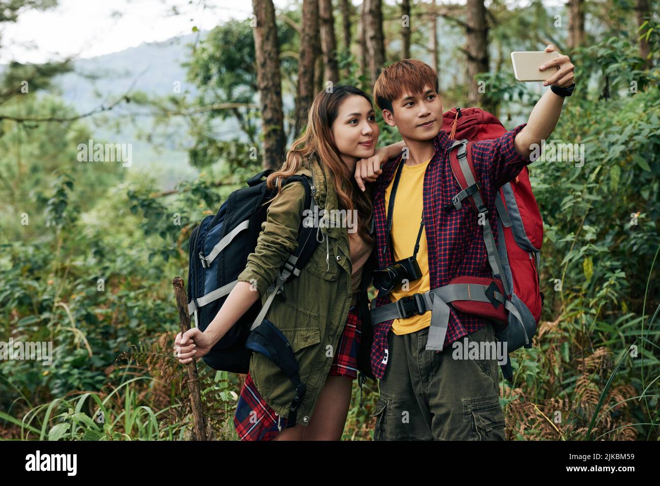 Junges Paar, das zusammen im Wald fotografiert Stockfoto