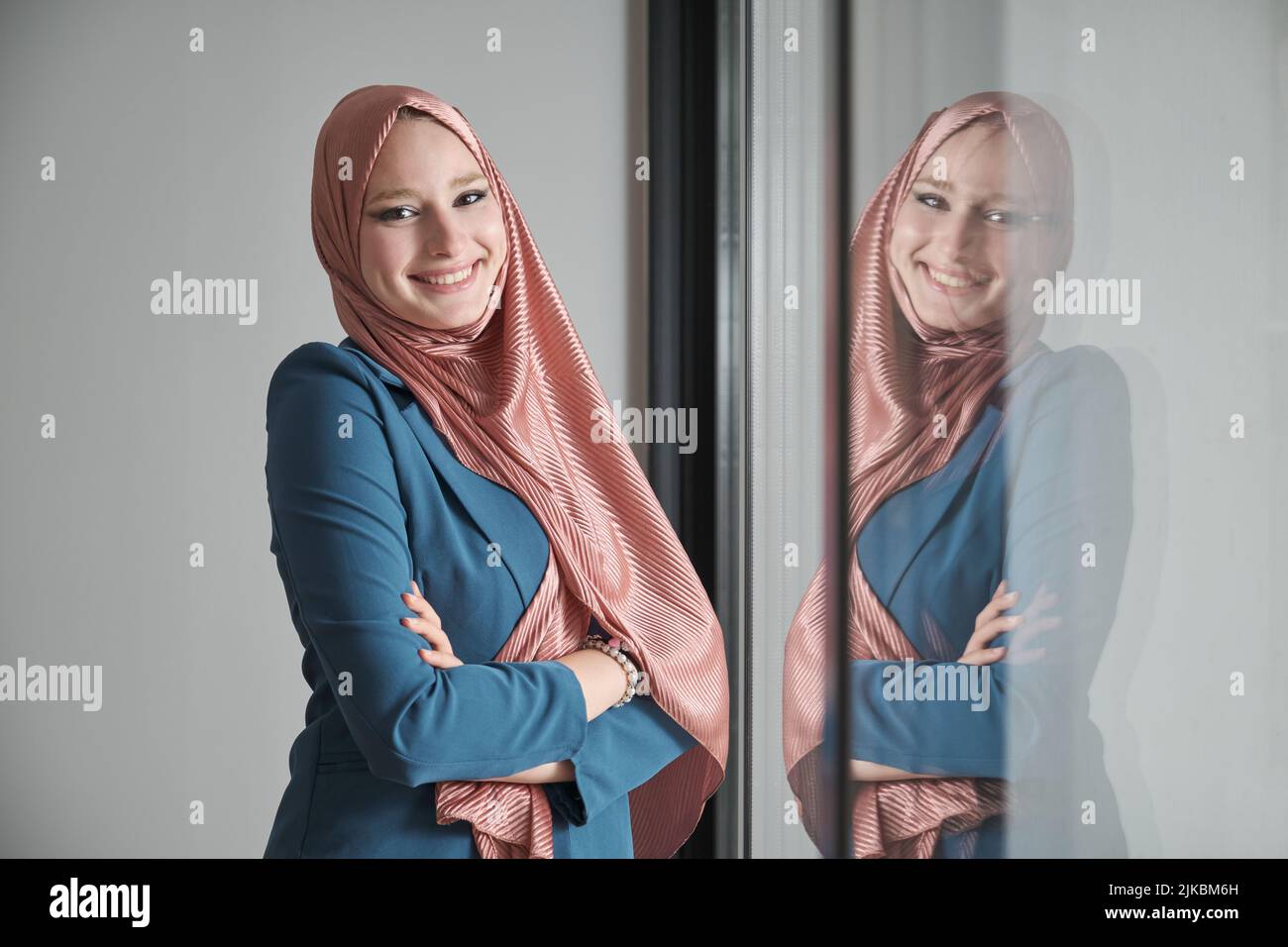 Porträt einer Geschäftsfrau, die lächelt und Hijab im Büro neben einem Fenster trägt. Stockfoto