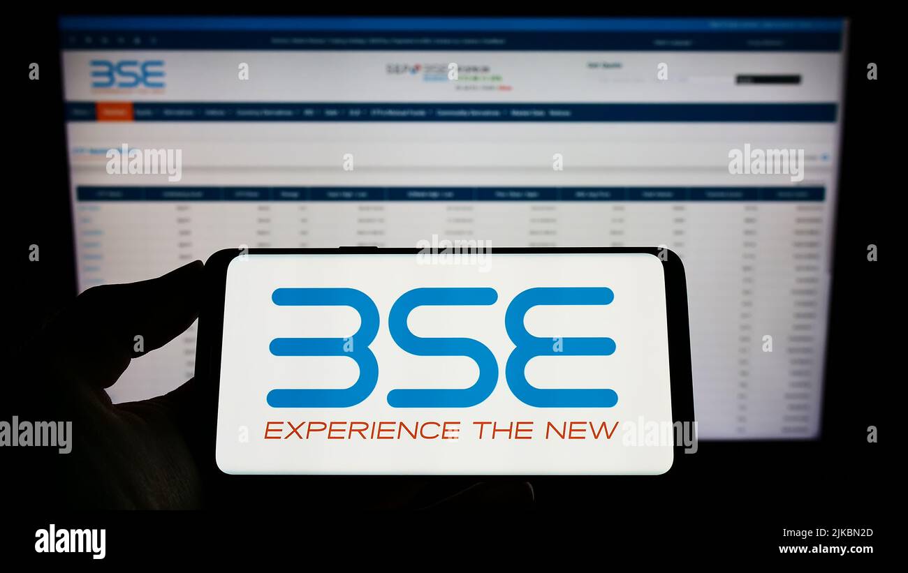 Person, die ein Mobiltelefon mit dem Logo der Firma BSE Limited (Bombay Stock Exchange) auf dem Bildschirm vor der Webseite hält. Konzentrieren Sie sich auf die Telefonanzeige. Stockfoto
