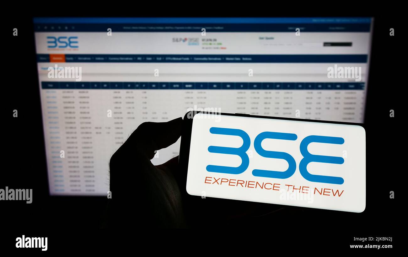Person, die Mobiltelefon mit dem Logo der Firma BSE Limited (Bombay Stock Exchange) auf dem Bildschirm vor der Business-Webseite hält. Konzentrieren Sie sich auf die Telefonanzeige. Stockfoto