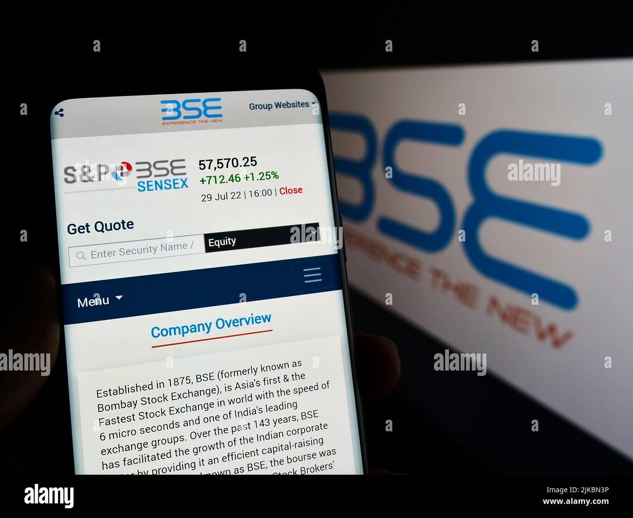 Person mit Mobiltelefon und Webseite der Firma BSE Limited (Bombay Stock Exchange) auf dem Bildschirm mit Logo. Fokusmitte von auf dem Telefon-Display. Stockfoto