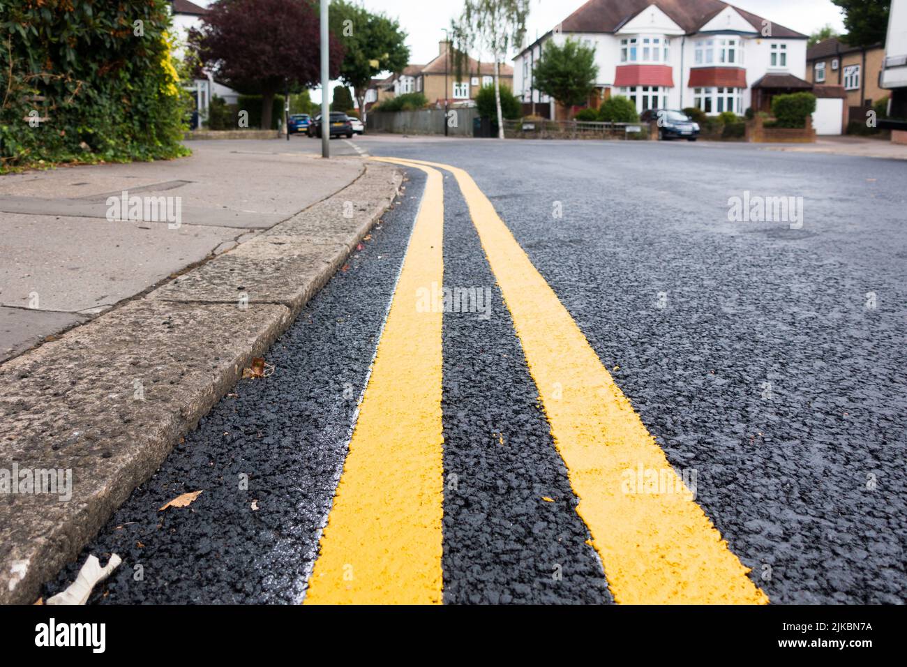 Doppelte gelbe Markierung auf dem Anflug auf eine Abbiegung in der britischen Straße Stockfoto