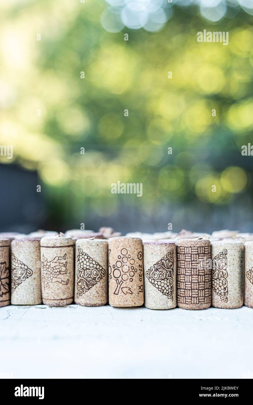 Vertikale Reihe von Korken, auf einem weißen Holztisch und mit einem natürlichen grünen Hintergrund. Grüner negativer Bereich außerhalb des Fokus. Konzept der Natur im Freien. Version Stockfoto