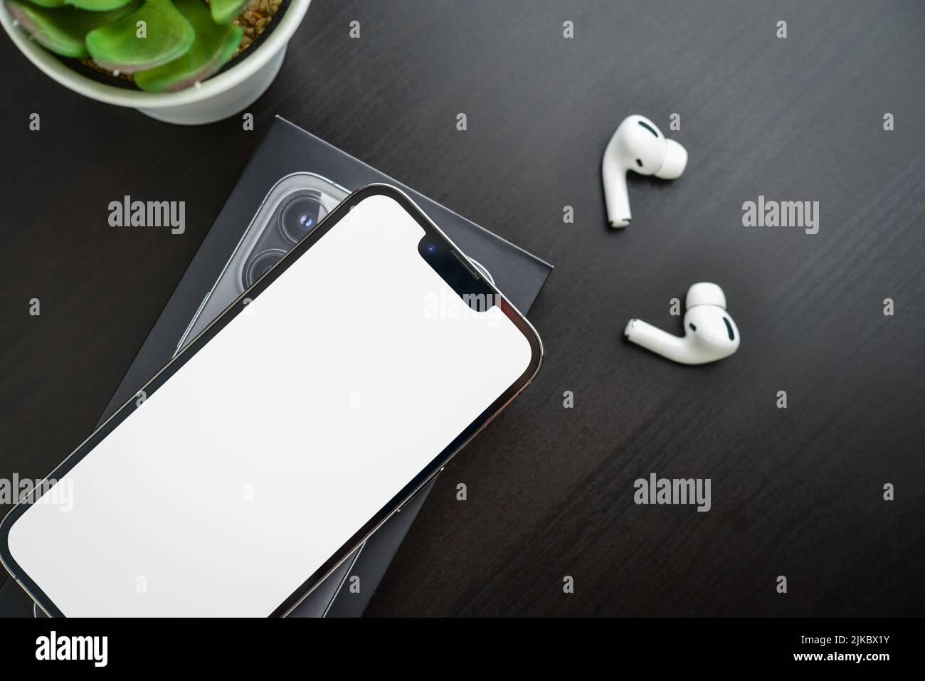 KIEW, UKRAINE - 10. FEBRUAR 2022: Ausgepackt neues Apple iPhone 13 Pro Space Grey mit leerer Seite und AirPods Pro Kopfhörern auf schwarzem Hintergrund. Stockfoto