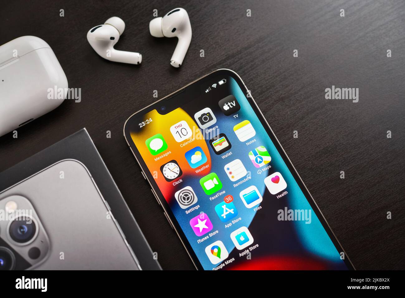 KIEW, UKRAINE - 10. FEBRUAR 2022: Ausgepacktes neues Apple iPhone 13 Pro Space Grey mit AirPods Pro Kopfhörern auf schwarzem Hintergrund. Stockfoto