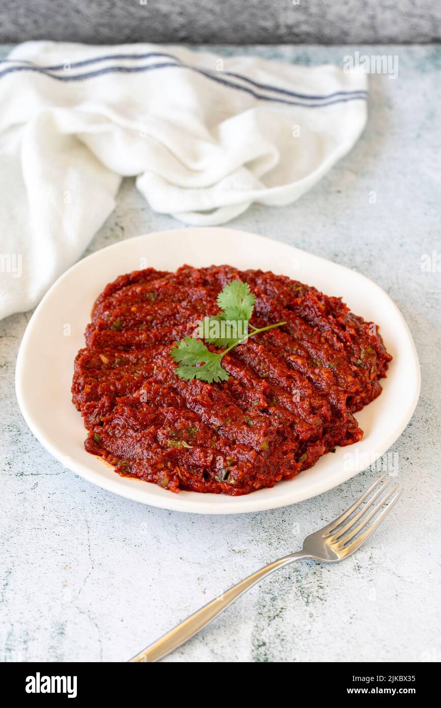 Adjika oder Chili-Paste. Scharfe Chilischoten, Harissa-Sauce. Würzige Paste Vorspeise auf einem Stein Hintergrund. Nahaufnahme Stockfoto