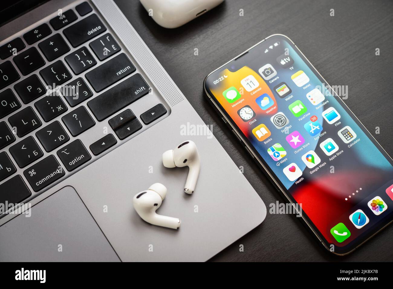 KIEW, UKRAINE - 10. FEBRUAR 2022: Apple-Produkt. MacBook Pro, iPhone 13 Pro mit AirPods Pro Kopfhörern auf schwarzem Hintergrund Draufsicht. Technologie-ga Stockfoto