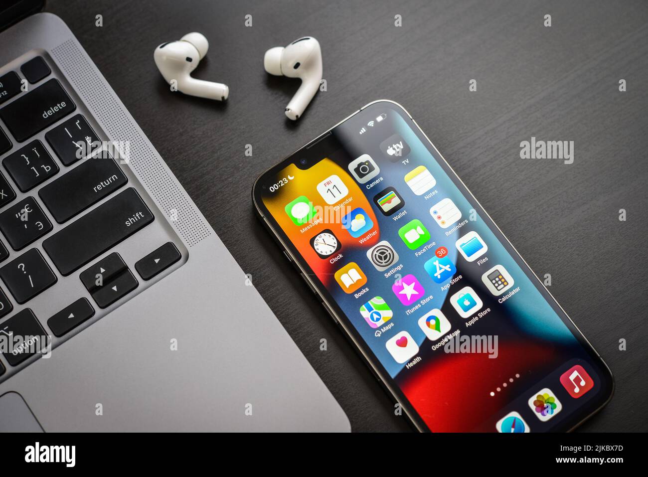 KIEW, UKRAINE - 10. FEBRUAR 2022: Apple-Produkt. MacBook Pro, iPhone 13 Pro mit AirPods Pro Kopfhörern auf schwarzem Hintergrund Draufsicht. Technologie-ga Stockfoto