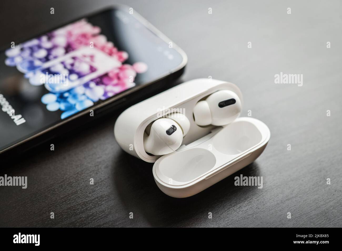 KIEW, UKRAINE - 10. FEBRUAR 2022: Ladetasche und das neue iPhone 13 Pro mit Apple Musik-App auf dem Bildschirm neben New Apple Computers AirPods Pro hea Stockfoto
