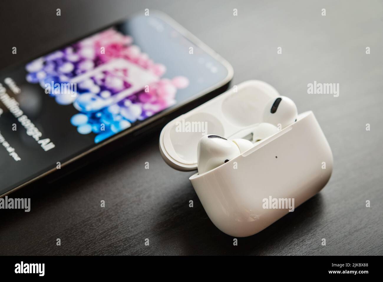 KIEW, UKRAINE - 10. FEBRUAR 2022: Ladetasche und das neue iPhone 13 Pro mit Apple Musik-App auf dem Bildschirm neben New Apple Computers AirPods Pro hea Stockfoto