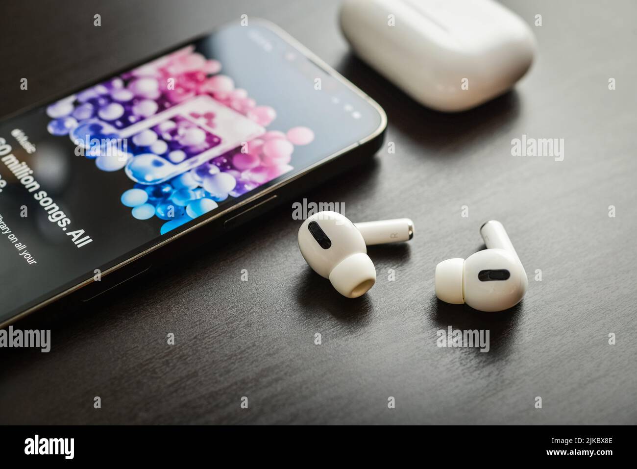 KIEW, UKRAINE - 10. FEBRUAR 2022: Ladetasche und das neue iPhone 13 Pro mit Apple Musik-App auf dem Bildschirm neben New Apple Computers AirPods Pro hea Stockfoto
