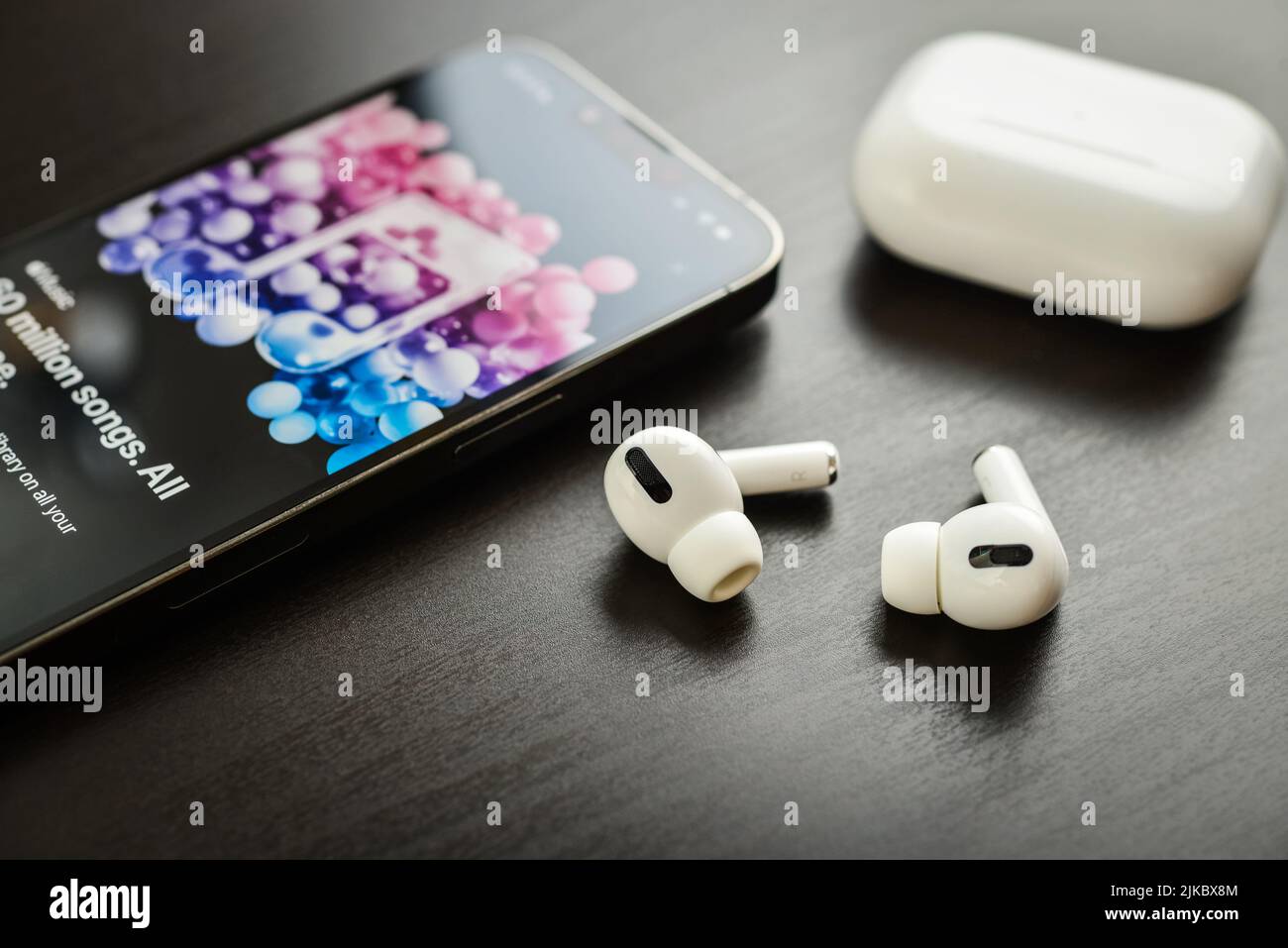KIEW, UKRAINE - 10. FEBRUAR 2022: Ladetasche und das neue iPhone 13 Pro mit Apple Musik-App auf dem Bildschirm neben New Apple Computers AirPods Pro hea Stockfoto