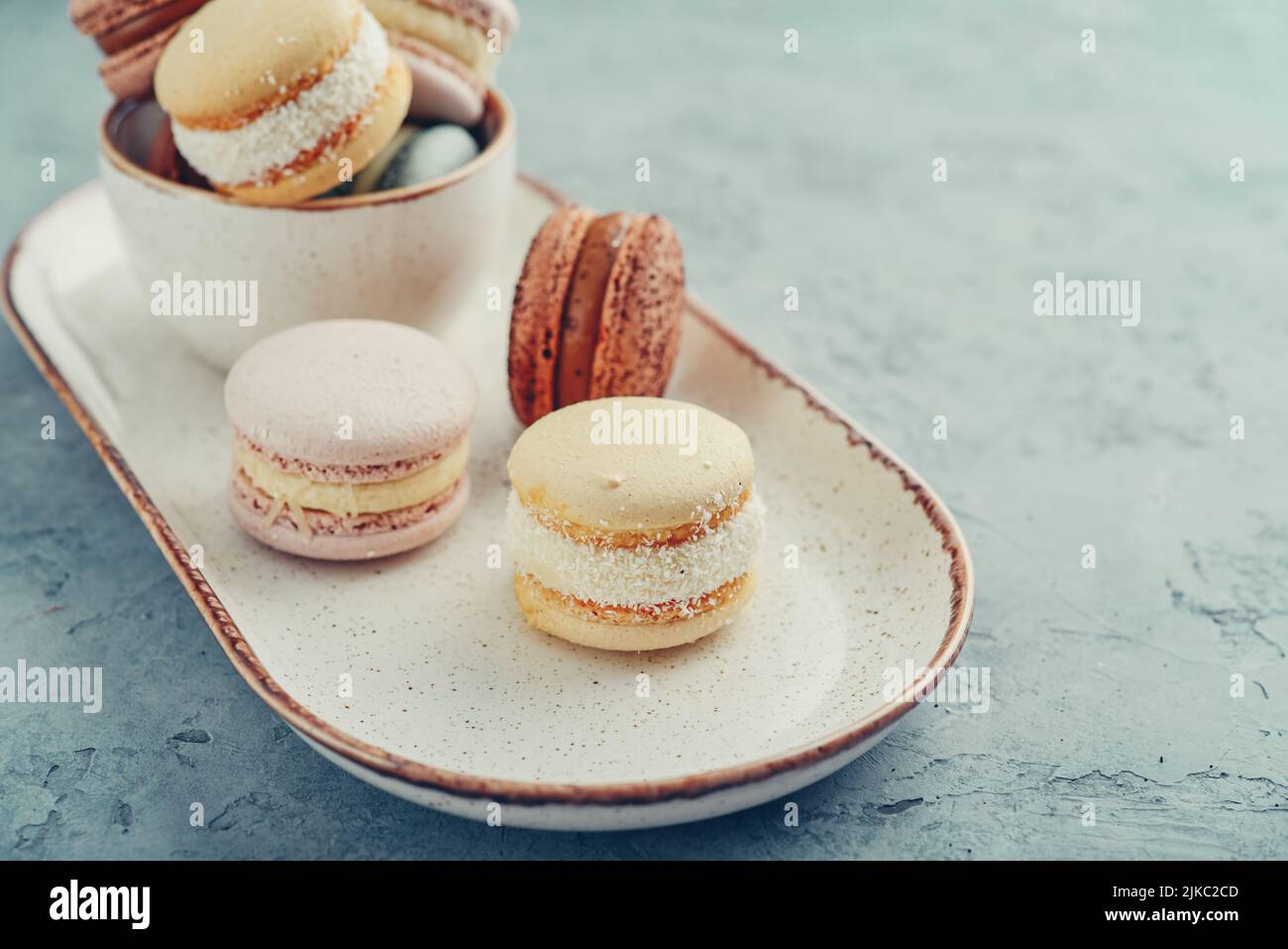 Bunte französische Macarons auf dem Teller auf blauem Hintergrund Stockfoto