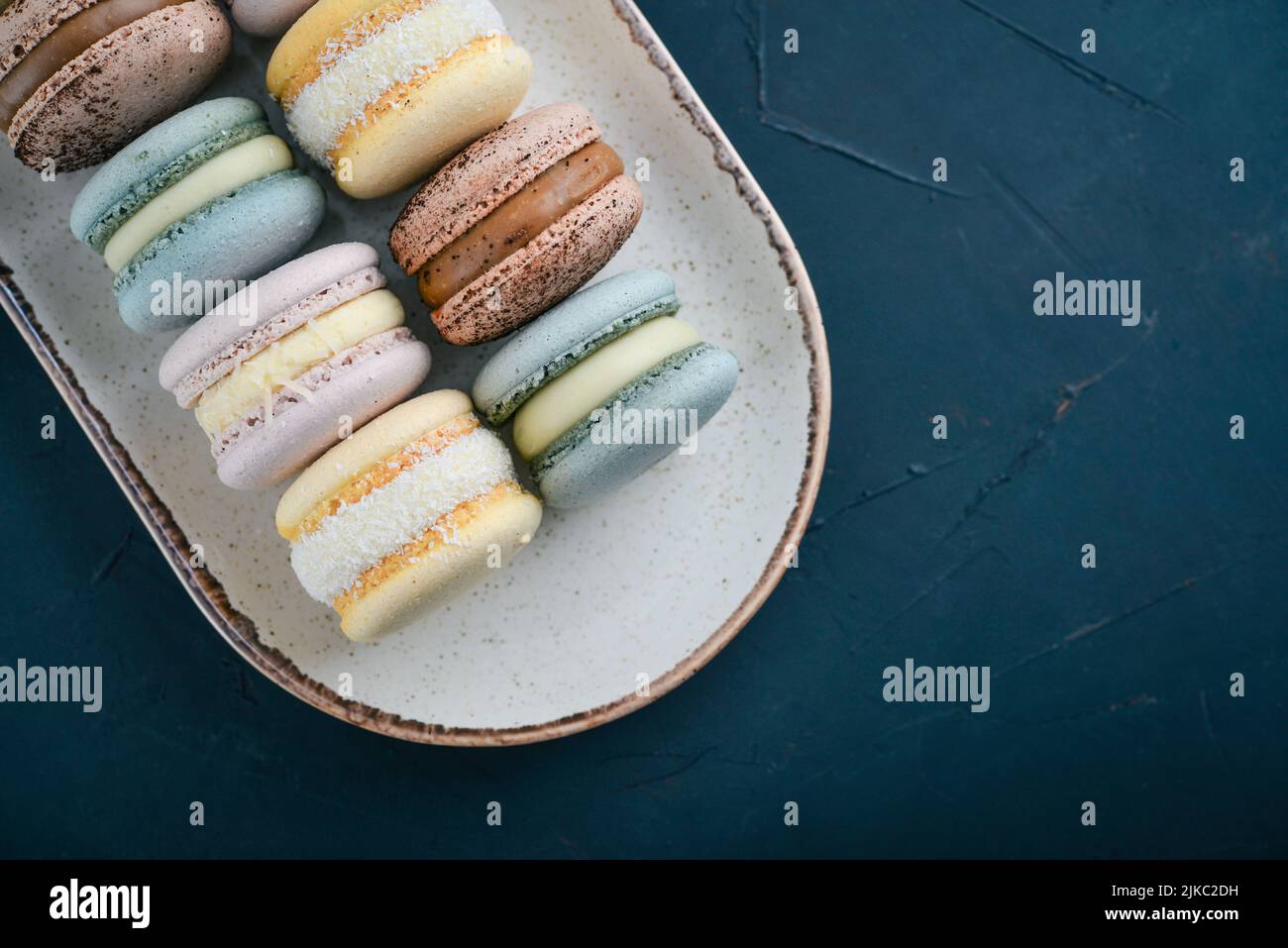 Bunte französische Macarons auf Teller auf schwarzem Hintergrund Stockfoto